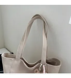 Detailed view of beige canvas tote bag texture with cute plush bear keychain accessory
