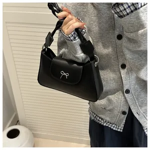 Dettaglio borsa nera in pelle con fiocco in argento e manico intrecciato alla moda