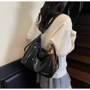 Détail du grand sac hobo noir avec fermetures éclair décoratives et glands en cuir souple
