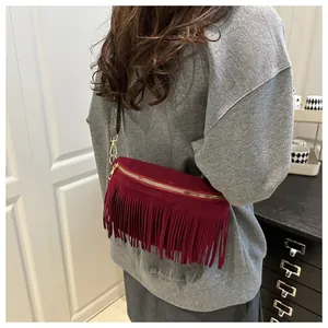 Close-up of a burgundy suede crossbody bag with long fringes and jacquard strap