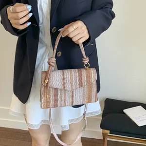 Detail of colorful woven straw handbag with a knotted handle and striped pattern design