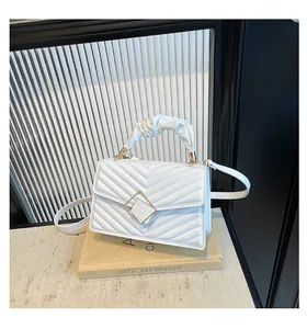 Close-up of white chevron quilted handbag with pleated handle and square metal clasp