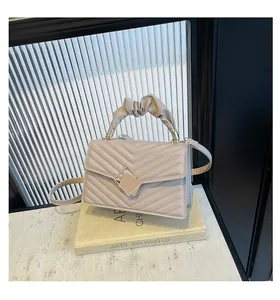 Detail of light brown quilted handbag with pleated handle and metal lock on book display