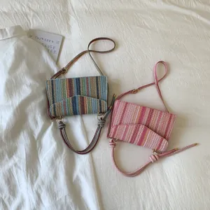 Close-up of woven straw crossbody bags with colorful stripes and knot handle detail