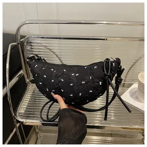 Detail of black pleated dumpling bag with white bow patterns and slim knot shoulder strap
