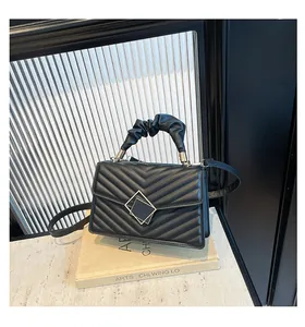 Black chevron quilted handbag with ruched handle and square metal clasp closeup.