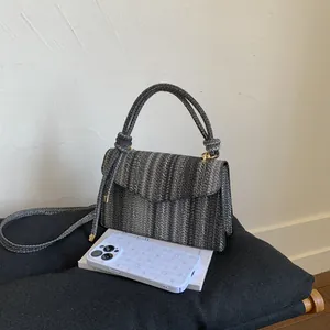 Close-up of woven vertical stripes on a handbag with a golden clasp and rope handle