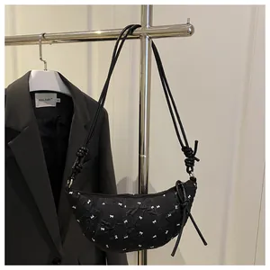 Close-up of pleated crescent bag featuring white bowknot prints and knotted shoulder strap