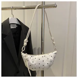 Detail of white dumpling bag featuring textured embossing and delicate black bows
