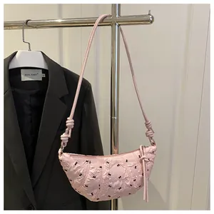 Close-up of pink quilted dumpling bag with black bows and knot shoulder strap detail