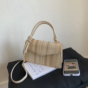 Detailed texture of straw woven envelope handbag with cylindrical handle and strap