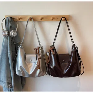 Détail des sacs fourre-tout argentés et marrons avec pendentifs en T métalliques sur crochet
