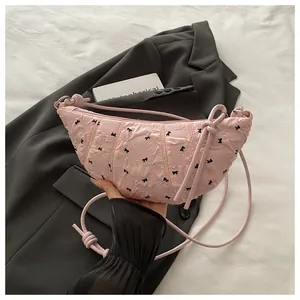 Detail of pink dumpling bag with bow pattern showing textured fabric and knotted strap