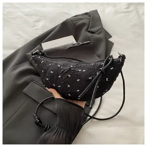 Detail of black pleated croissant bag with white ribbon embroidery and zipper closure