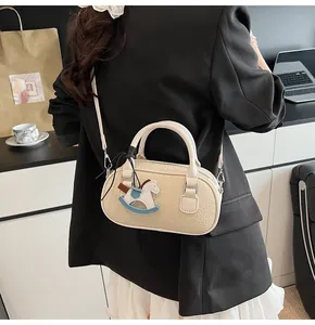 Detail of a creamy beige lychee grain mini bowling bag with a horse charm and slim strap