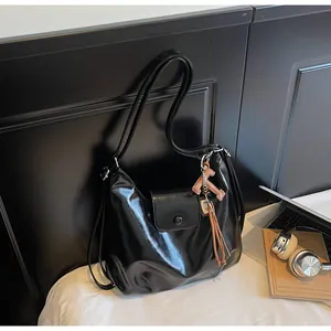 Détail du sac cabas noir brillant avec pendentif en lettre T et franges élégantes