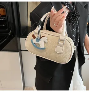 Detail of cream bowling bag with lychee texture and blue rocking horse charm
