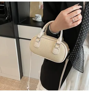 Detail of creamy litchi grain faux leather bowling bag with silver hardware and strap