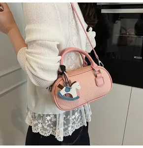 Pink lychee texture bowling bag with horse charm detail shown on model in kitchen