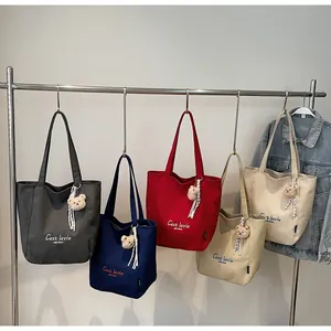 Détail de sacs cabas en toile multicolores avec pendentif ours sur un support