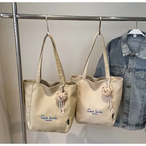 Détail du sac cabas en toile avec broderie bleue et pendentif en forme d'ours mignon