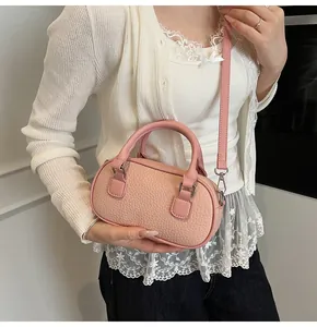 Close-up of pink lychee grain leather boston bag held by model with silver hardware