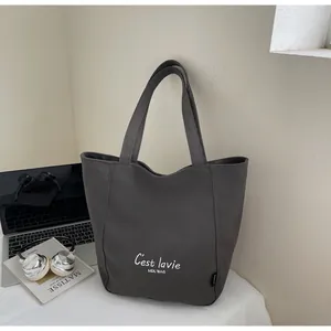 Détail du sac cabas en toile gris foncé avec lettrage blanc et bandoulière épaisse