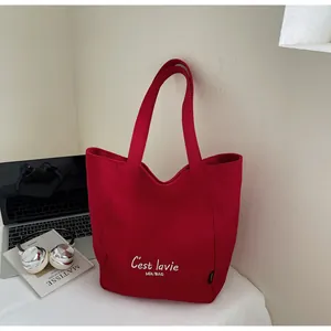 Gros plan d'un sac cabas en toile rouge avec broderie blanche C'est lavie élégante