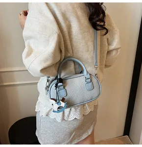 Detail of light blue textured leather bowling bag with horse charm and crossbody strap