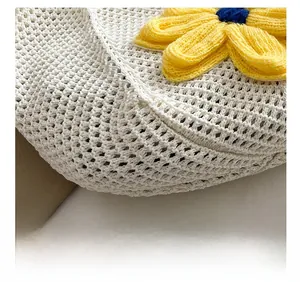 Detail view of white knit mesh tote featuring large yellow and blue floral embroidery