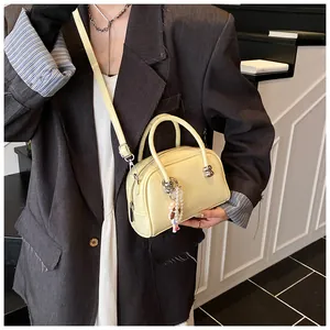 Detail of cream minimalist bowling bag with pearl doll charm and adjustable strap