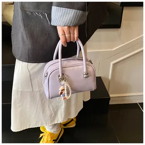 Detail of light purple glossy mini Boston bag featuring a pearl doll charm and silver zipper