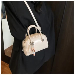 Chic beige square Boston bag with pearl charm shown worn as a crossbody bag