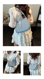 Detail view of a light blue woven crescent shoulder bag with metallic lock and strap