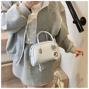 Detail of light blue square handbag with pearl pendant and adjustable shoulder strap