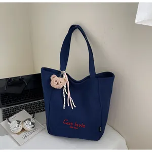 Détail du sac cabas en toile marine avec broderie rouge et breloque ours en peluche