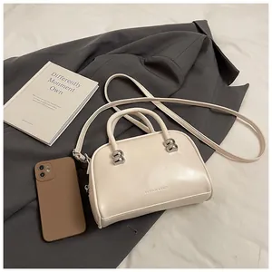 Close-up of cream Boston handbag with silver metal ball hardware and fashion text detail