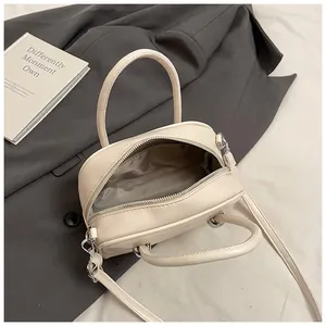 Close-up of beige square handbag with open zipper showing gray fabric lining and storage