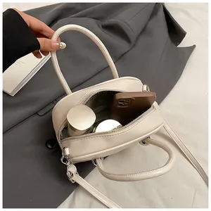 Top-down view of cream leather box bag interior showing capacity for phone and cosmetics