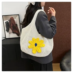 Detail of white crochet tote bag with large yellow flower shown on model's shoulder