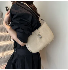 Detailed view of cream woven shoulder bag with silver clasp on model with black outfit