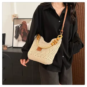 Détail du sac cabas tissé beige avec poignée en perles de bois et bandoulière