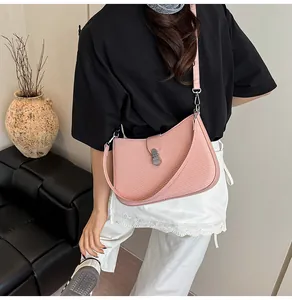 Detailed shot of pink woven shoulder bag with silver buckle worn by a model