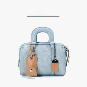 Detail of light blue Boston bag with brown leather tag and silver chain strap