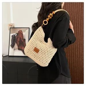 Détail du sac beige tissé main avec perles en bois et écusson en cuir