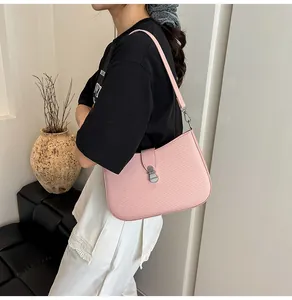 Close-up of pink textured crossbody bag with silver hardware on a casual model