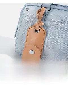 Detail view of light blue fabric bag with brown leather accent and silver hardware