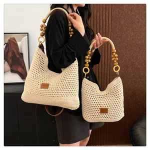 Détail de deux sacs cabas tissés beige avec anses en perles de bois et logos en cuir