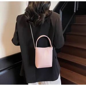 Detailweergave van de roze mini emmerzak van leer met een zilveren kettingriem