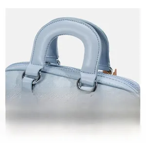 Close-up of blue denim Boston bag with light blue leather handle and silver metal hardware